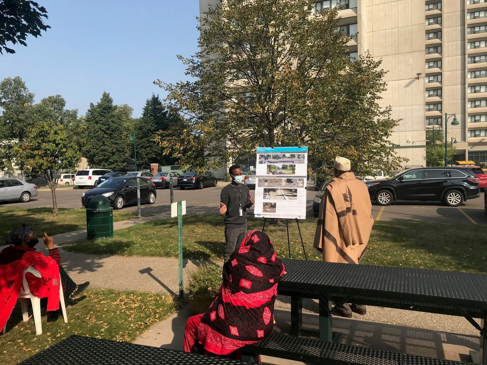 Abdullahi Abdulle presenting street design boards to residents outside an apartment tower